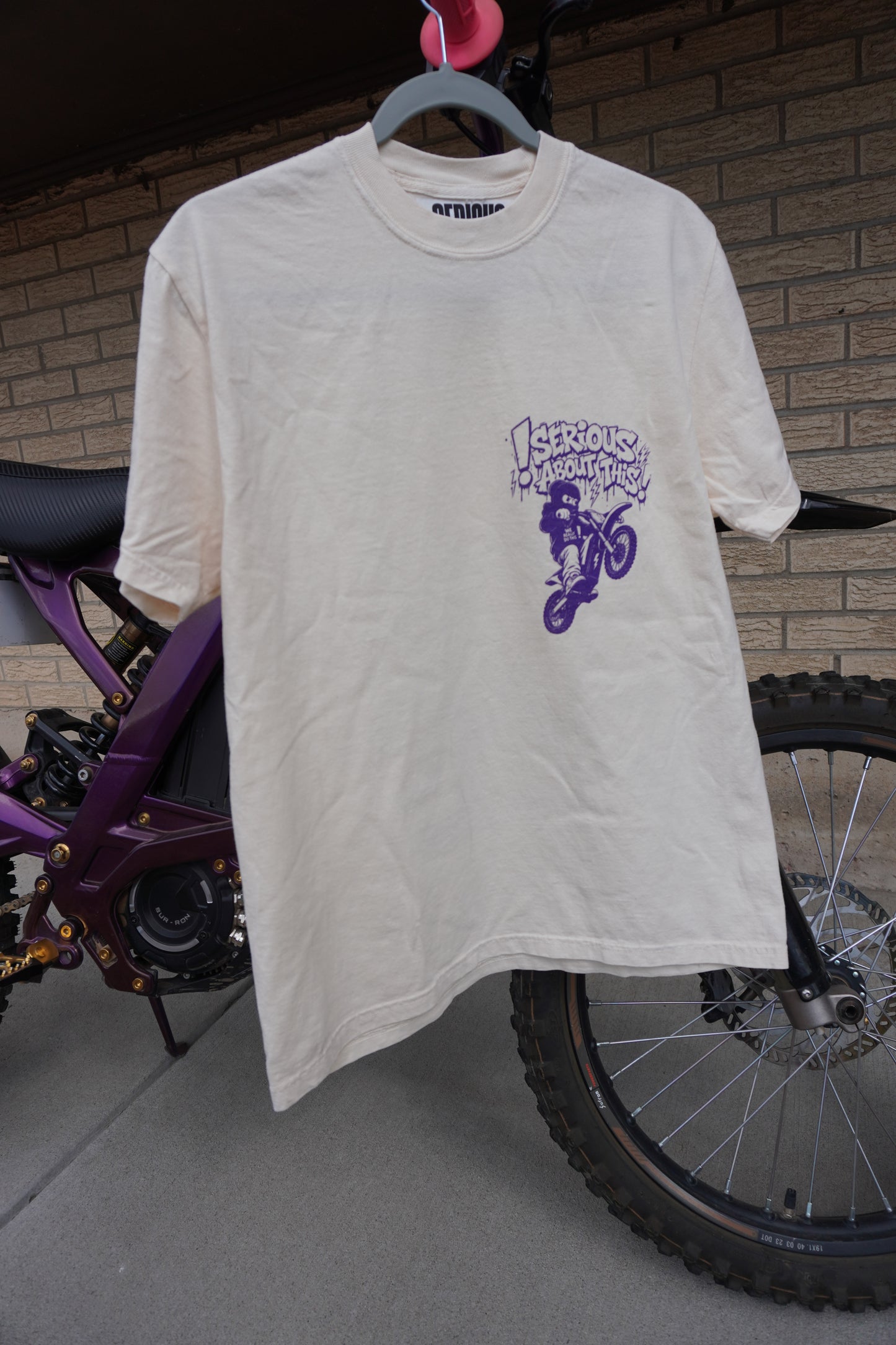 “Riding Regardless” - tan and purple t shirt
