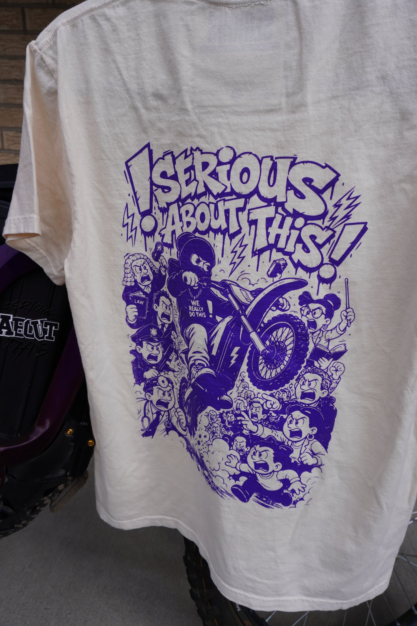 “Riding Regardless” - tan and purple t shirt